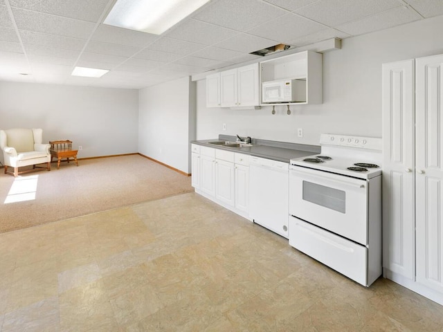 kitchen with white appliances, a paneled ceiling, light flooring, a sink, and white cabinetry