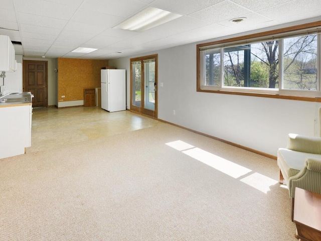 unfurnished living room featuring baseboards, plenty of natural light, a paneled ceiling, and french doors