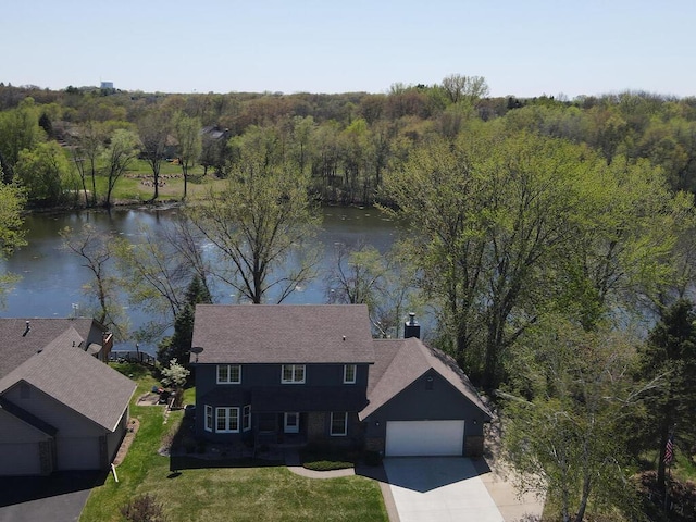 view from above of property featuring a nearby body of water and a heavily wooded area