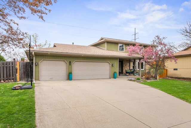 traditional-style home with concrete driveway, fence, a front yard, and a garage