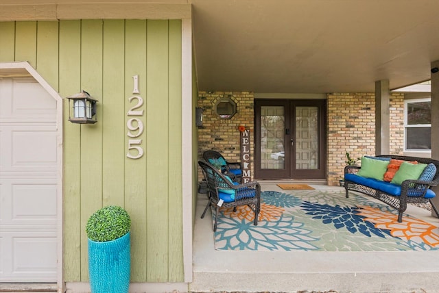 doorway to property featuring french doors, covered porch, and brick siding