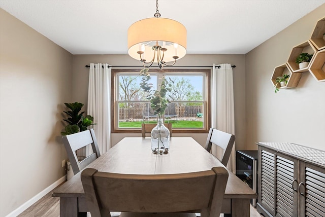 dining room with baseboards, a notable chandelier, and light wood-style flooring