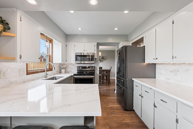 kitchen featuring open shelves, a sink, white cabinets, a peninsula, and stainless steel appliances