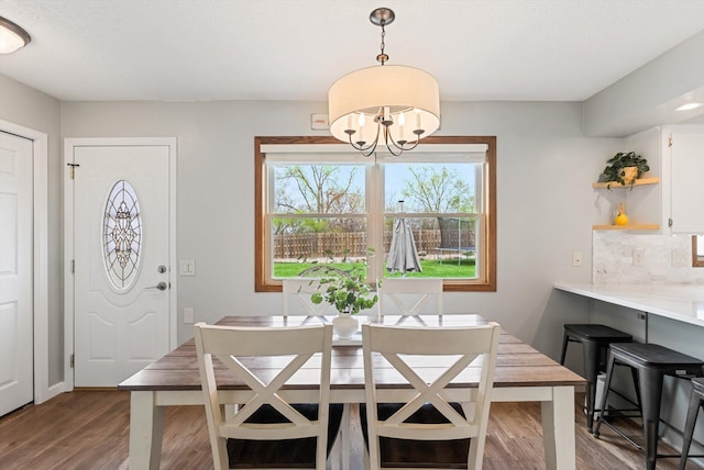 dining area featuring dark wood-style flooring and a notable chandelier