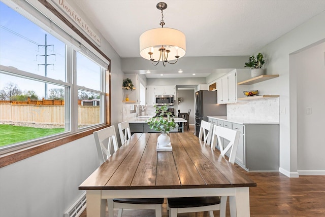 dining space with baseboards, dark wood finished floors, and an inviting chandelier