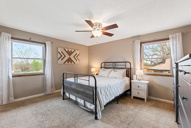 bedroom featuring a textured ceiling, baseboards, light colored carpet, and multiple windows