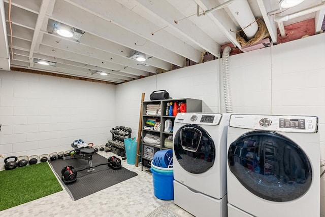 washroom with concrete block wall, separate washer and dryer, and laundry area