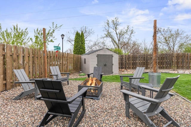 view of patio featuring a storage shed, an outdoor structure, a fenced backyard, and a fire pit
