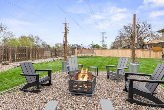 view of yard with a fenced backyard, a trampoline, and an outdoor fire pit