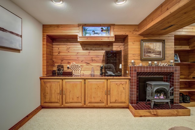 living area with light colored carpet, a wood stove, and wooden walls