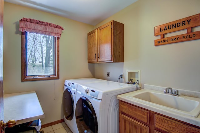 washroom featuring cabinet space, a sink, baseboards, light tile patterned flooring, and washer and dryer