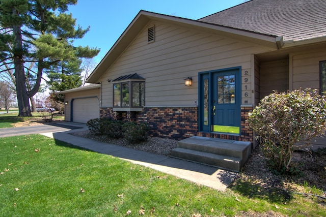 view of front of home featuring roof with shingles, a front lawn, brick siding, a garage, and driveway