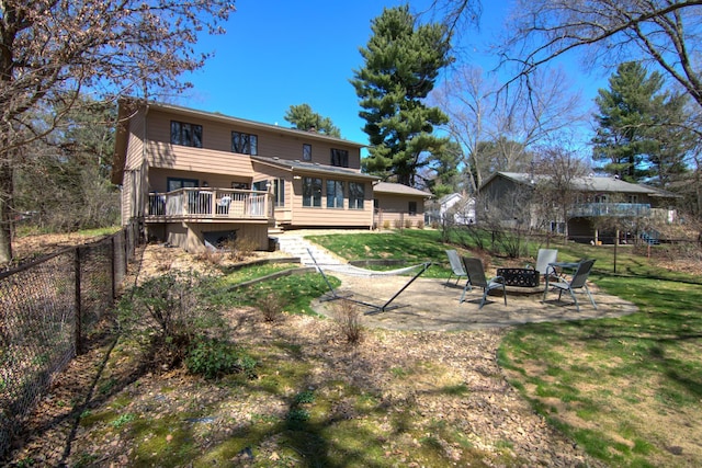 back of house with a yard, a fire pit, a fenced backyard, and a wooden deck