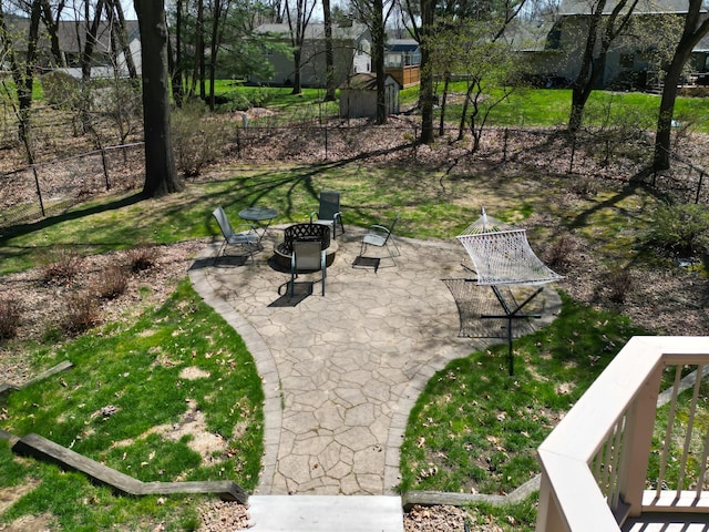 view of community with a lawn, an outdoor fire pit, a patio area, and fence