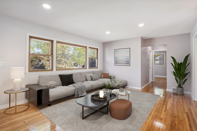 living area featuring baseboards, light wood-type flooring, and recessed lighting