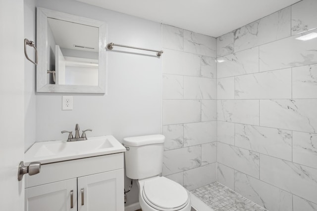 bathroom with vanity, toilet, and a tile shower