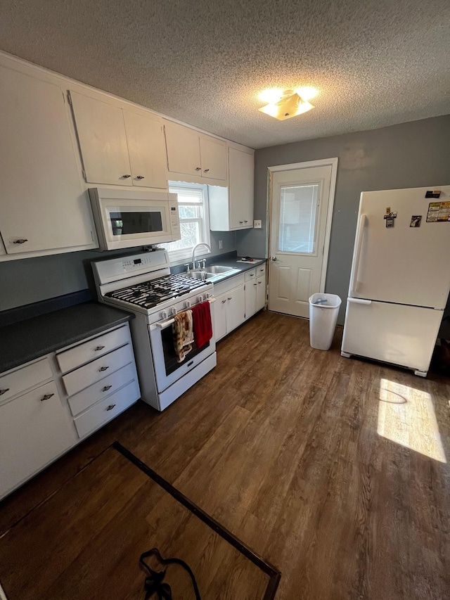 kitchen with white appliances, a sink, dark wood-type flooring, a textured ceiling, and white cabinets