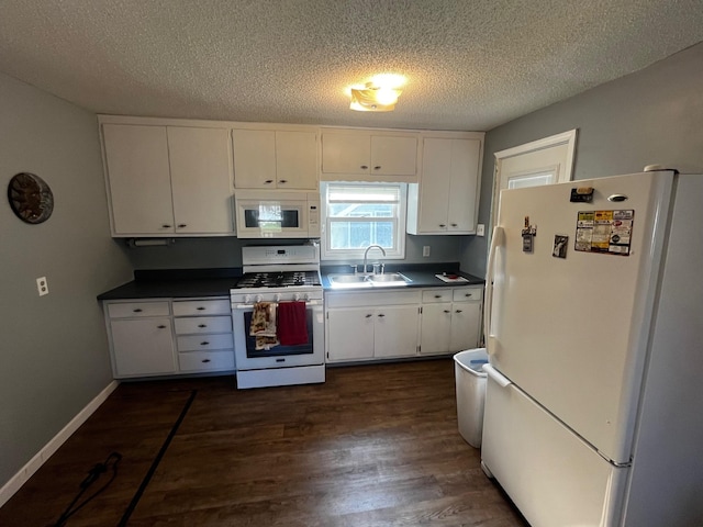 kitchen with white appliances, a sink, dark wood finished floors, dark countertops, and a textured ceiling
