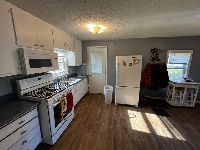kitchen featuring white appliances, a sink, dark wood finished floors, a textured ceiling, and white cabinetry