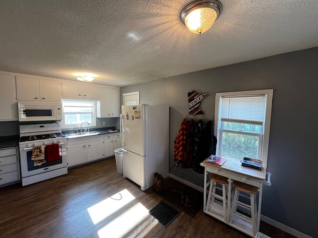 kitchen featuring white appliances, a sink, a textured ceiling, dark wood finished floors, and white cabinets