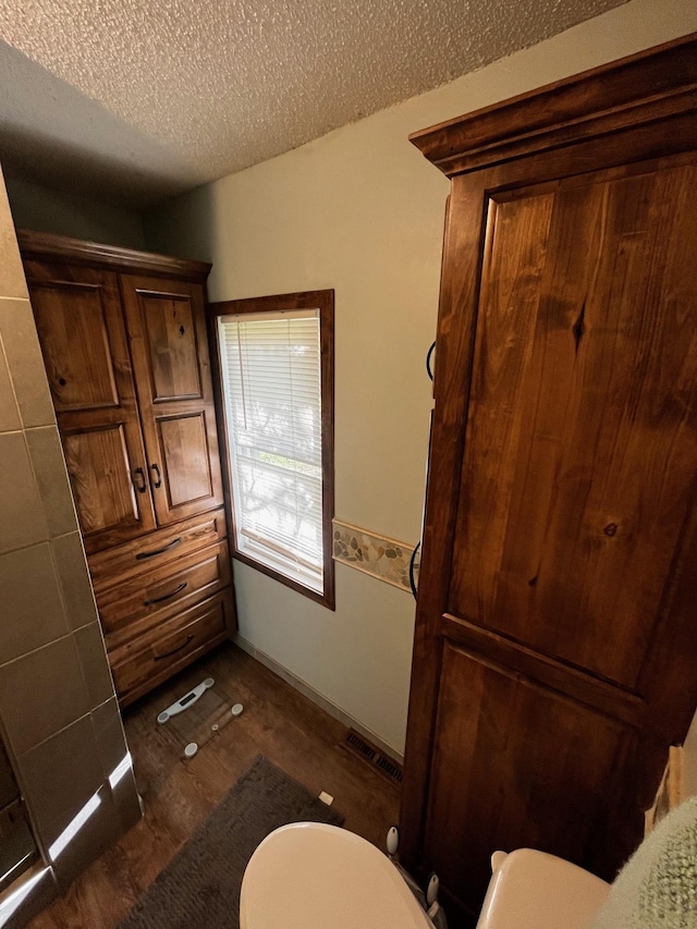 bathroom with toilet, wood finished floors, and a textured ceiling