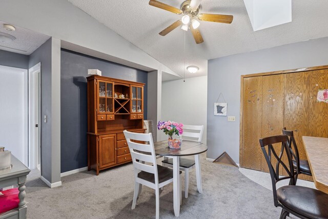 dining room with baseboards, a ceiling fan, a textured ceiling, and light carpet