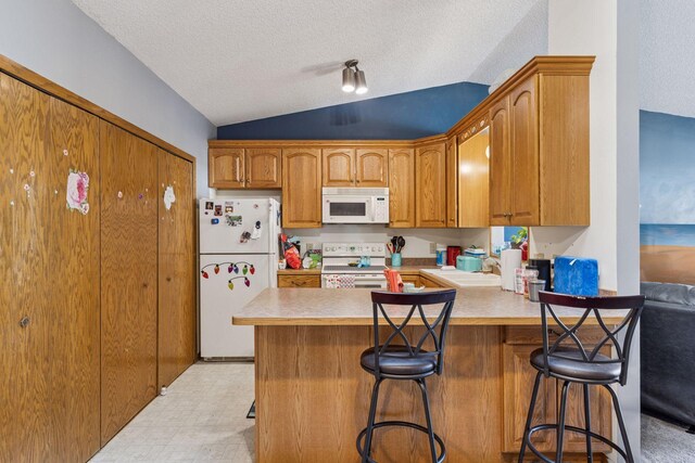 kitchen with a textured ceiling, vaulted ceiling, brown cabinets, a peninsula, and white appliances