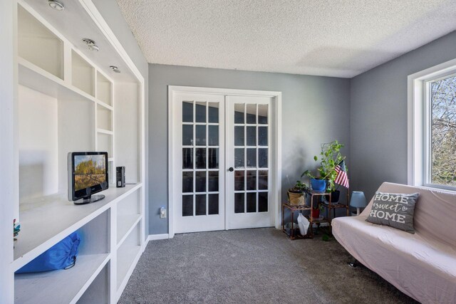sitting room featuring french doors, a textured ceiling, and carpet