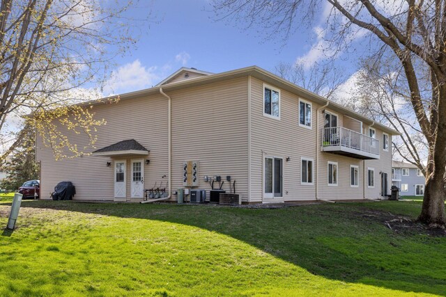 rear view of property with a lawn, a balcony, and central air condition unit