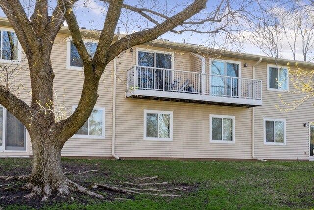 back of house with a yard and a balcony