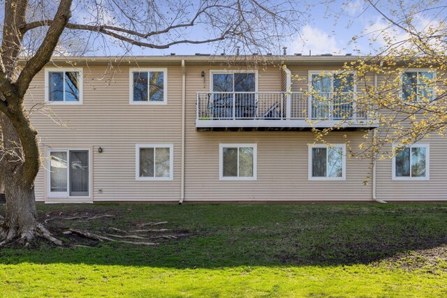 back of house with a lawn and a balcony