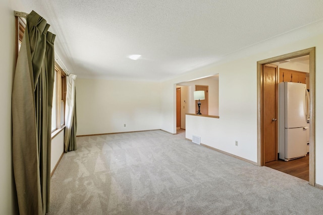 6309 Halifax Dr, Brooklyn Center, MN 55429 - unfurnished living room featuring visible vents, a textured ceiling, baseboards, and light carpet
