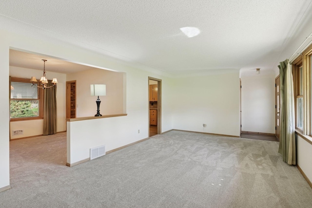 6309 Halifax Dr, Brooklyn Center, MN 55429 - spare room with carpet flooring, a textured ceiling, a chandelier, baseboards, and visible vents