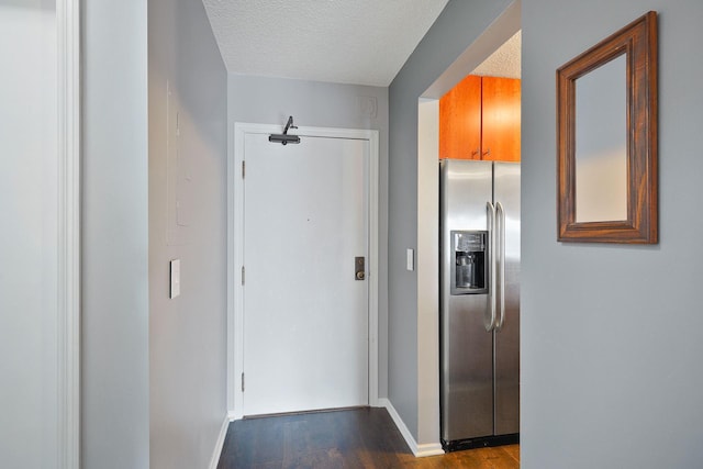 corridor featuring baseboards, dark wood-style flooring, and a textured ceiling