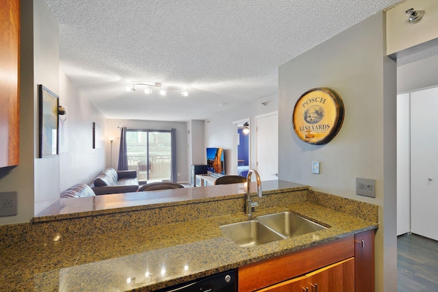 kitchen with dark wood finished floors, brown cabinets, a sink, stone countertops, and open floor plan