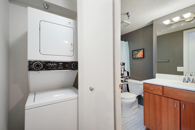 laundry room featuring tile patterned flooring, a sink, a textured ceiling, and stacked washer / drying machine