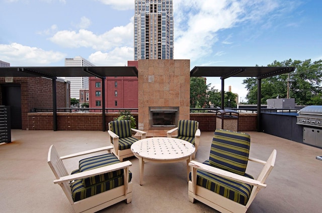 view of patio / terrace featuring grilling area, a glass covered fireplace, and exterior kitchen
