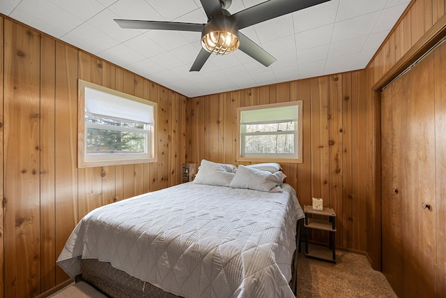 23920 Camp Dr, Daniels Twp, WI 54872 - bedroom featuring multiple windows, light carpet, wooden walls, and a ceiling fan