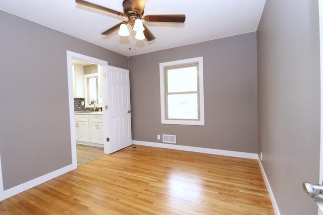10424 Washburn Ave S, Bloomington, MN 55431 - unfurnished bedroom featuring light wood finished floors, baseboards, connected bathroom, and ceiling fan