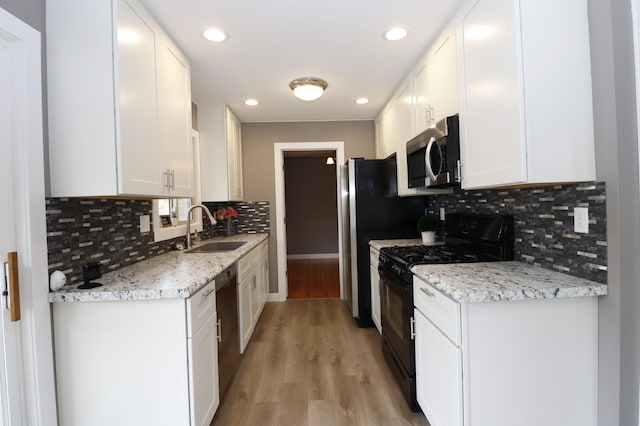 10424 Washburn Ave S, Bloomington, MN 55431 - kitchen featuring appliances with stainless steel finishes, a sink, white cabinetry, light wood finished floors, and decorative backsplash