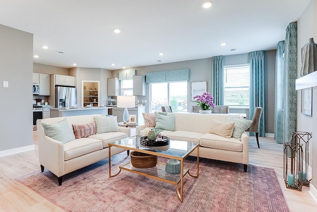 living room featuring recessed lighting, baseboards, and light wood-style flooring