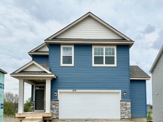 view of front of house featuring an attached garage, a shingled roof, and stone siding