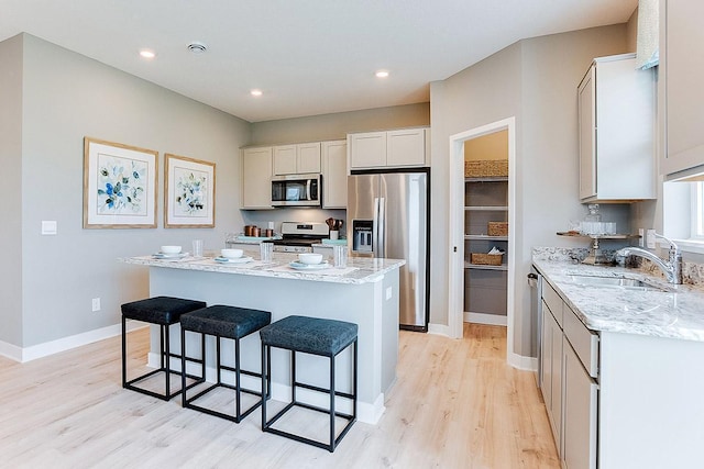 kitchen with light wood-style floors, a breakfast bar area, a center island, a sink, and appliances with stainless steel finishes