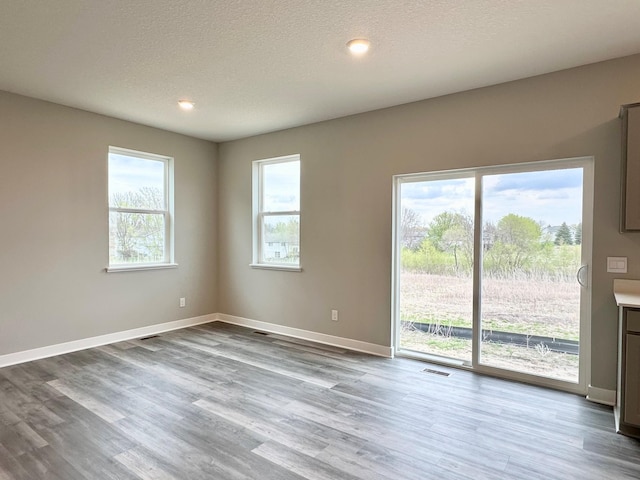 spare room with visible vents, wood finished floors, baseboards, recessed lighting, and a textured ceiling
