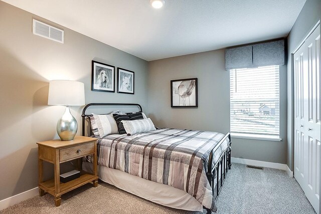 bedroom with visible vents, baseboards, a closet, and light carpet
