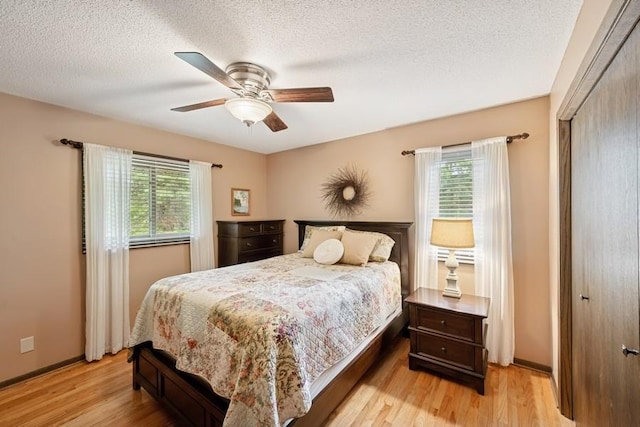 16523 243rd Ave NW, Orrock Twp, MN 55309 - bedroom with multiple windows, light wood-style floors, a textured ceiling, a ceiling fan, and baseboards