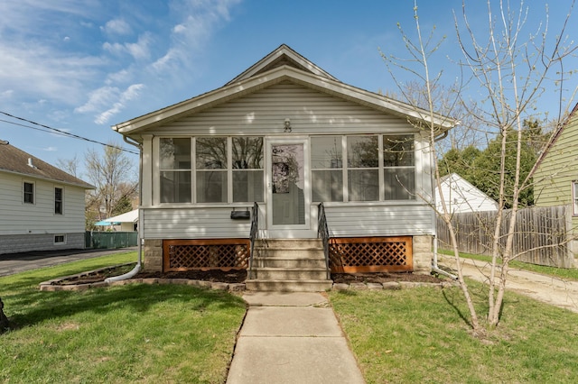 view of front facade with a front yard, fence, and a sunroom