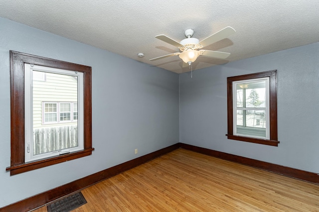 spare room with ceiling fan, a textured ceiling, baseboards, light wood-type flooring, and visible vents