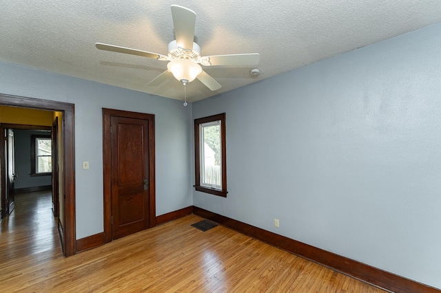 unfurnished bedroom featuring baseboards, visible vents, multiple windows, and light wood-style floors