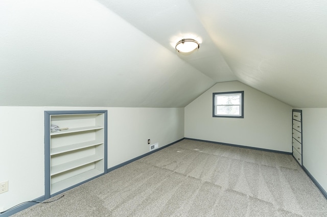 bonus room featuring built in features, baseboards, carpet, and vaulted ceiling